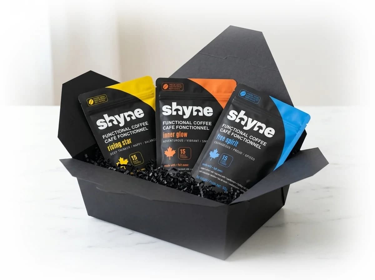 Open black gift box holding three Shyne coffee pouches in black crinkle paper